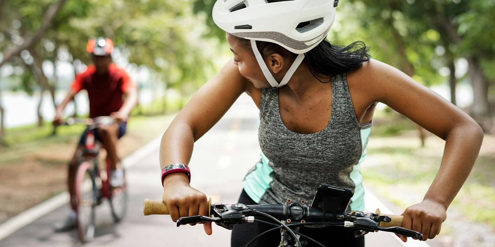 Woman biking, looking back towards her partner